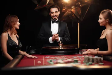 SINAGPH Live Casino — Join thrilling real-dealer tables A professional dealer in a tuxedo greeting players at the roulette table, symbolizing the authentic live casino feel at SINAGPH.