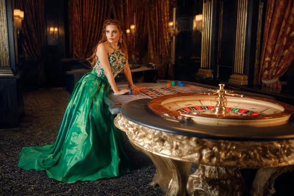SINAGPH — A high-class gaming experience without limits A woman in a luxurious green gown next to an ornate roulette wheel, capturing the upscale casino mood of SINAGPH.